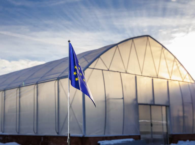EU-flagga framför växthus.