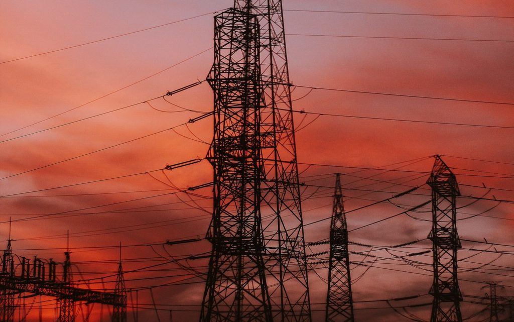 Picture of power lines at sunset. The sky turns red with light. 