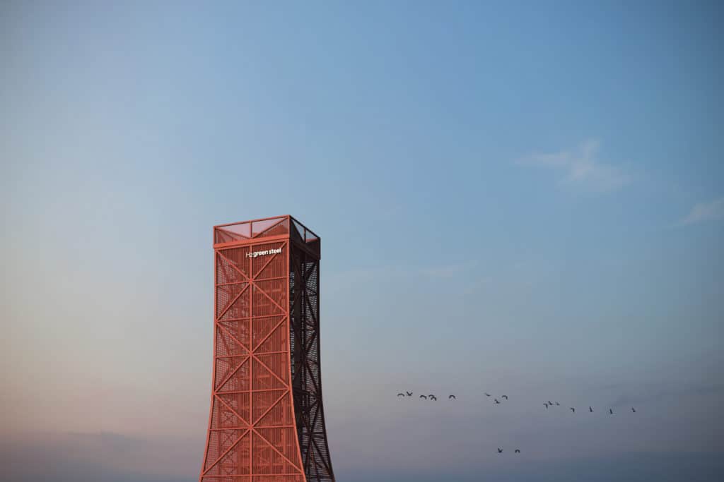 Red tower with H2 Green Steel on it and birds flying by the tower. 