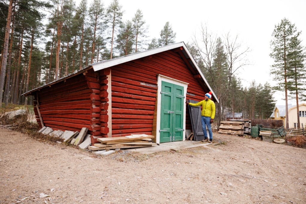 Iain Bramble vid en röd timring som ska bli hans ateljé