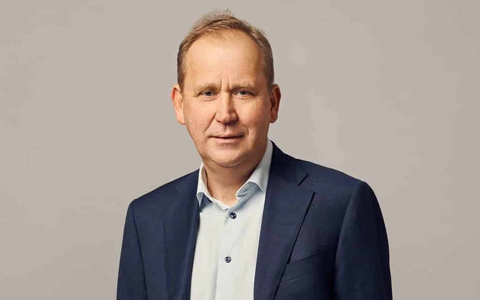 Porträtt av Per Langer, vd för Polar Energy, iklädd mörkblå kostym och ljus skjorta, stående mot en neutral grå bakgrund.