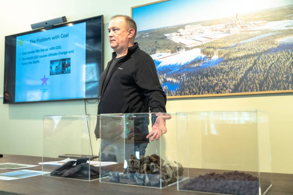 Nigel Fisher, Stegra, shows pictures on a powerpoint. In the foreground 3 glass boxes with coal, at the Stegra meeting place 