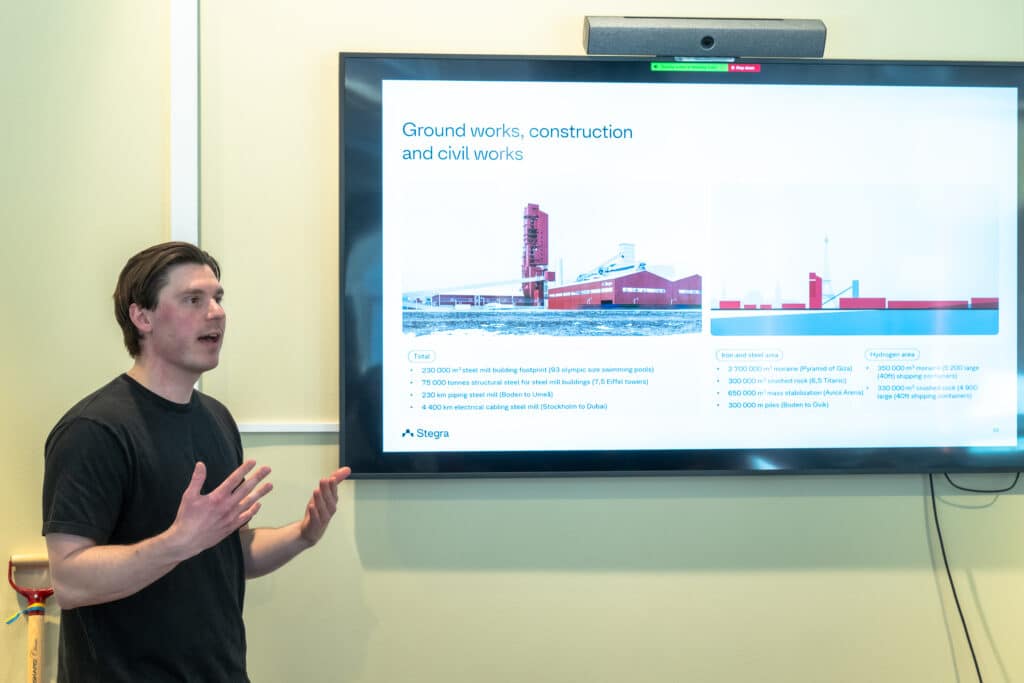 Philip Öhman, Stegra, gives a presentation with a steel mill picture in the background at the Stegra meeting place