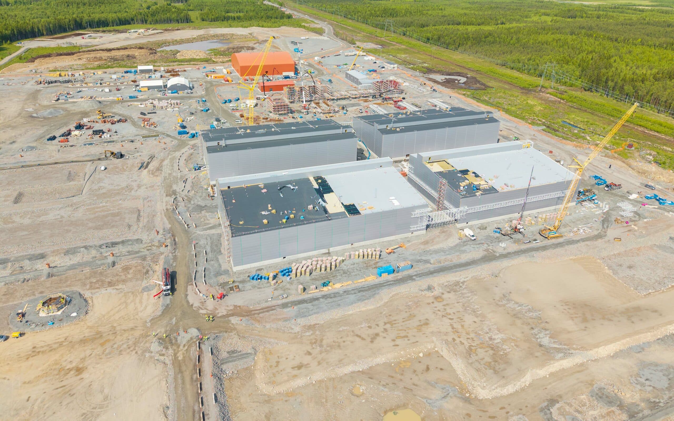 Flygbild över vätgasanläggningen på Boden Industrial Park med flera stora industribyggnader, byggkranar och markarbeten. Omgivande skog i bakgrunden.