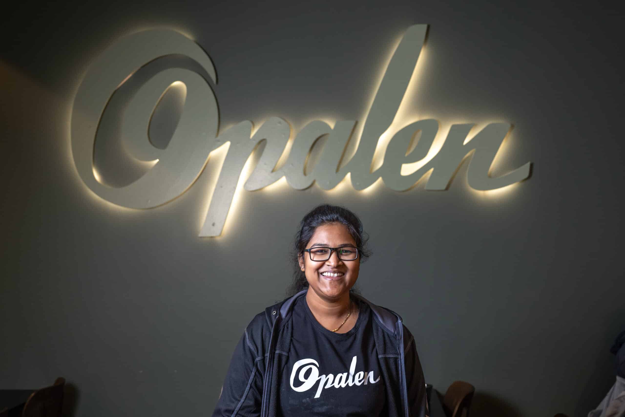 Naveena framför belyst skylt med texten Opalen