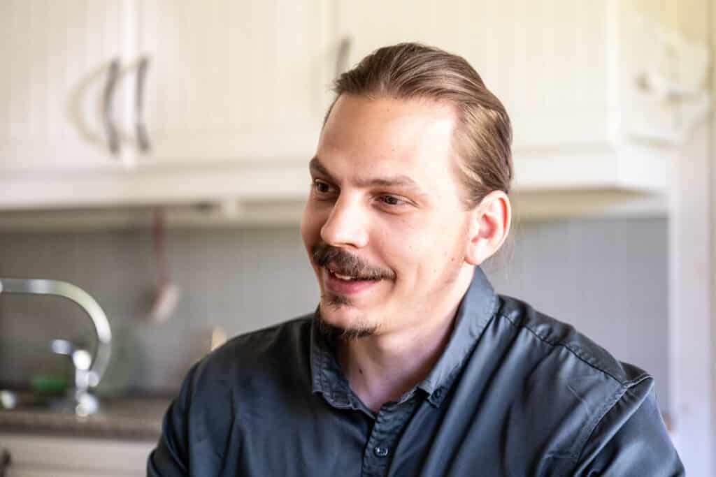 Man in a gray shirt indoors in a kitchen setting