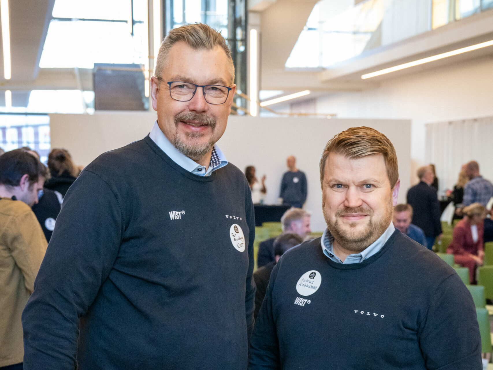 Två män står bredvid varandra och ser glada ut.